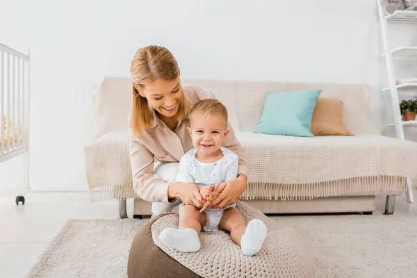 Mère souriante étreignant adorable tout-petit dans la chambre de pépinière — Photo de stock