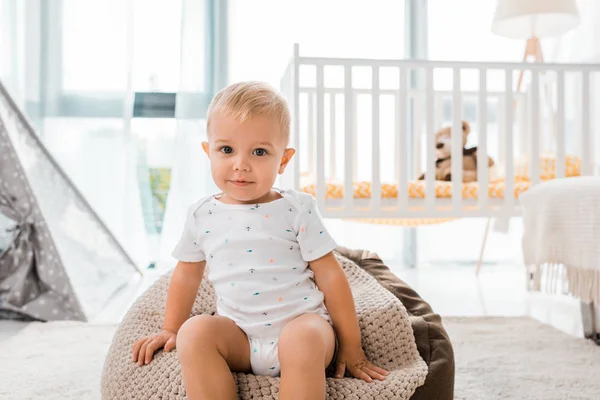 Adorabile bambino seduto sulla sedia sacchetto di fagioli e guardando la fotocamera all'interno nella stanza dei bambini — Foto stock