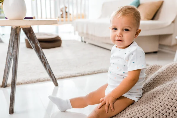 Entzückendes Kleinkind sitzt im Kinderzimmer und blickt in die Kamera — Stockfoto