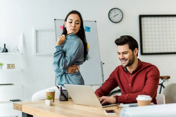 Multiethnic colleagues working on project and using laptop in office — Stock Photo