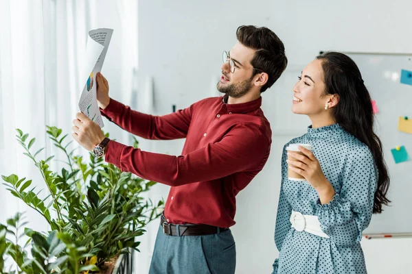 Multiethnic couple of architects looking at blueprint in office — Stock Photo