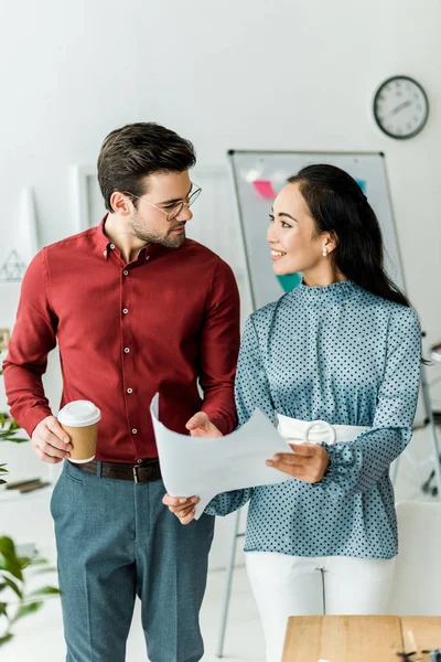 Smiling multicultural couple of architects working on blueprint in office — Stock Photo