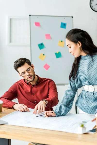 Selective focus of multicultural couple of architects working on blueprint in office — Stock Photo