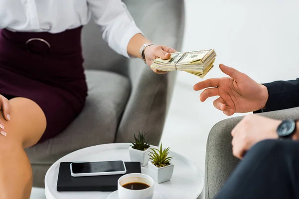 Cropped view of businesswoman giving money to businessman in office — Stock Photo