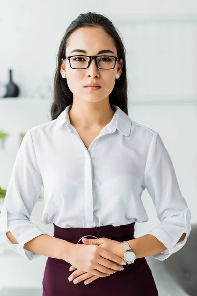 Beautiful confident asian businesswoman in formal wear with folded hands looking at camera — Stock Photo