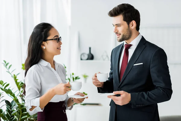 Lächelnde multiethnische Kollegen bei einer Kaffeepause im Büro — Stockfoto