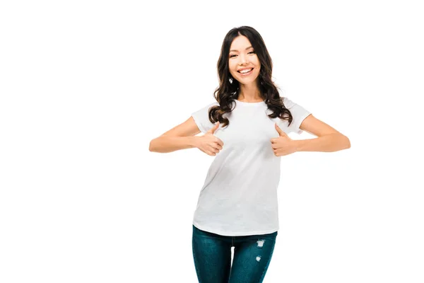 Happy brunette girl showing thumbs up and smiling at camera isolated on white — Stock Photo