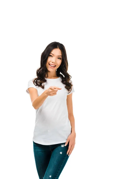 Attractive brunette girl pointing with finger and smiling at camera isolated on white — Stock Photo