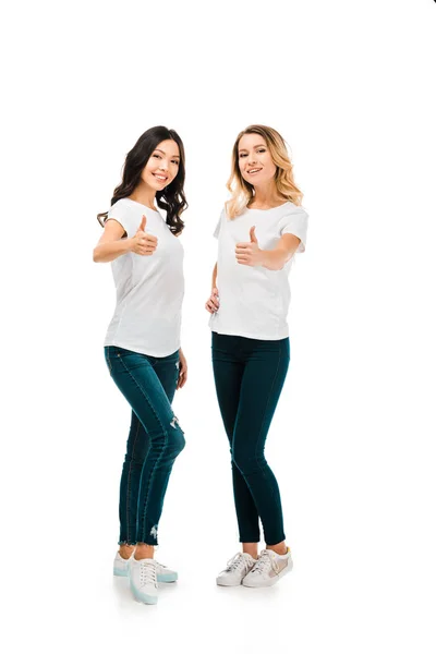 Full length view of happy young women showing thumbs up and smiling at camera isolated on white — Stock Photo