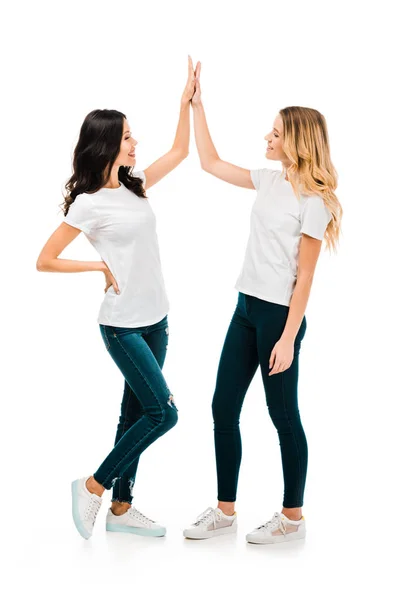 Glückliche junge Frauen geben High Five und lächeln einander isoliert auf weiß — Stockfoto