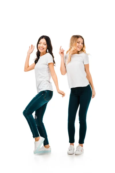 Vista completa de hermosas chicas felices en camisetas blancas bailando aisladas en blanco - foto de stock