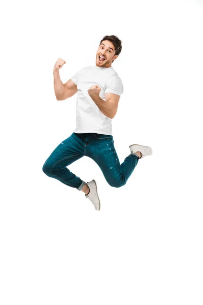 Excited young man jumping and smiling at camera isolated on white — Stock Photo