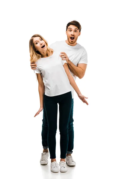 Visão de comprimento total do jovem casal surpreso em camisetas brancas olhando para a câmera isolada no branco — Fotografia de Stock