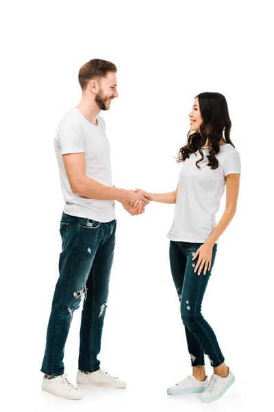 Feliz jovem casal apertando as mãos e sorrindo uns aos outros isolado no branco — Fotografia de Stock