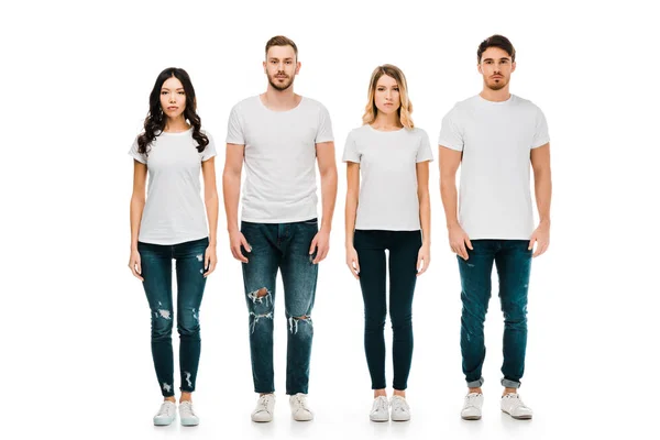 Vue pleine longueur de jeunes hommes et femmes sérieux en t-shirts blancs et pantalons en denim debout et regardant la caméra isolée sur blanc — Photo de stock