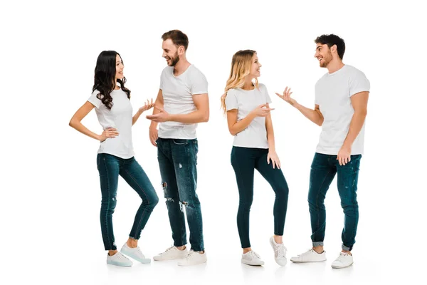 Vista de larga duración de parejas jóvenes de pie y hablando aislados en blanco - foto de stock