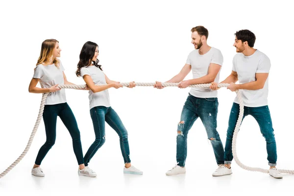 Smiling young friends pulling rope and playing tug of war isolated on white — Stock Photo