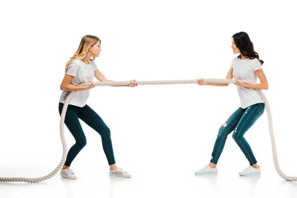 Jóvenes enojadas tirando de la cuerda y mirándose aisladas en blanco - foto de stock