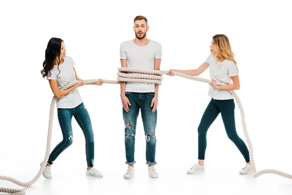 Young women holding rope around scared young man isolated on white — Stock Photo