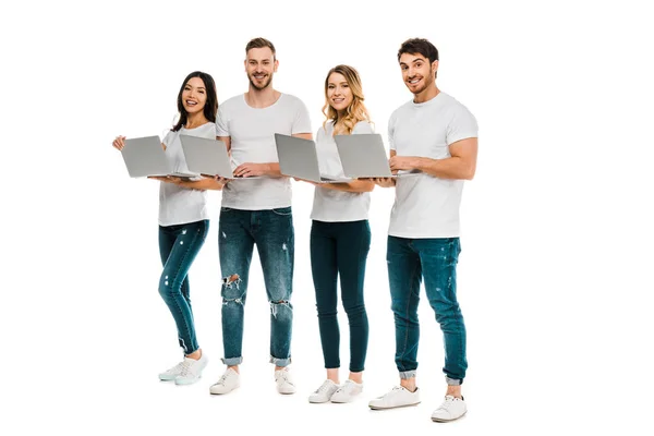 Happy young men and women standing with laptop and smiling at camera isolated on white — Stock Photo