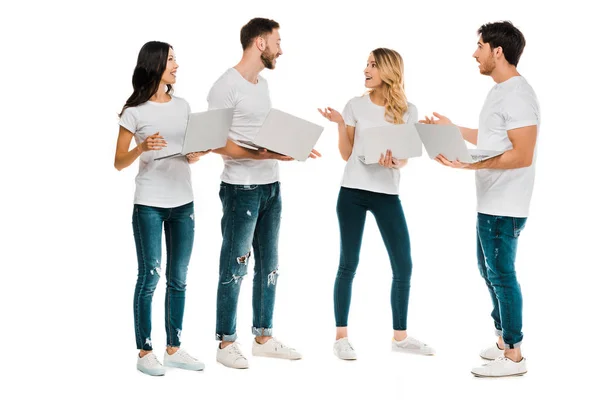 Jóvenes emocionales usando computadoras portátiles y hablando aislados en blanco - foto de stock