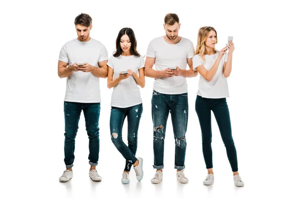 Full length view of young friends in white t-shirts and jeans using smartphones isolated on white — Stock Photo