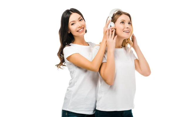 Meninas felizes bonitas em camisetas brancas usando fones de ouvido juntos isolados no branco — Fotografia de Stock