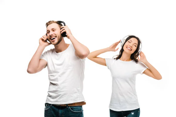 Alegre pareja joven en camisetas blancas escuchando música en auriculares aislados en blanco - foto de stock