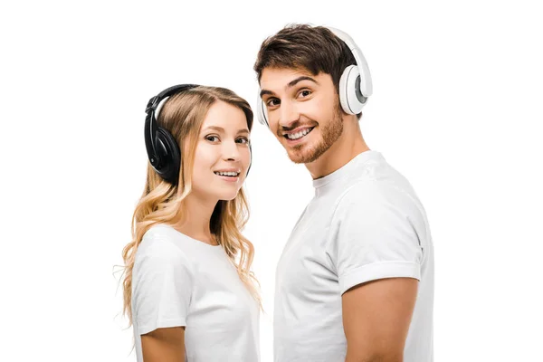 Щаслива молода пара в білих футболках і навушниках посміхається на камеру ізольовано на білому — стокове фото