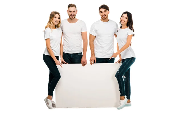 Jovens amigos alegres segurando cartaz em branco e sorrindo para a câmera isolada no branco — Fotografia de Stock
