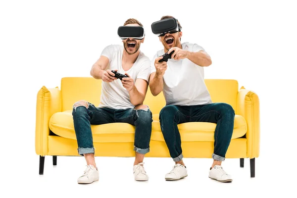 Jóvenes excitados en auriculares de realidad virtual jugando con joysticks aislados en blanco — Stock Photo