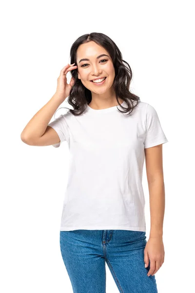 Bonita chica asiática en camiseta tocando el pelo aislado en blanco — Stock Photo