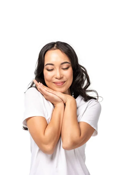 Asiatische Frau mit geschlossenen Augen, die gefaltete Arme in Gesichtsnähe hält, isoliert auf weiß — Stockfoto