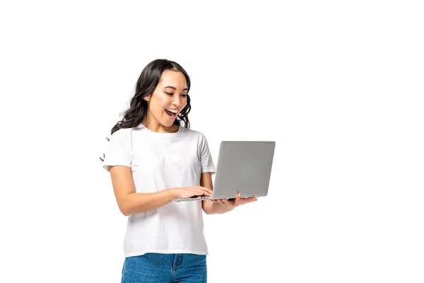 Riéndose joven asiático mujer usando laptop y levantando puño aislado en blanco - foto de stock