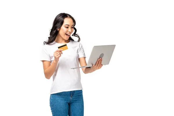 Eccitato asiatico donna utilizzando laptop e holding carta di credito isolato su bianco — Foto stock