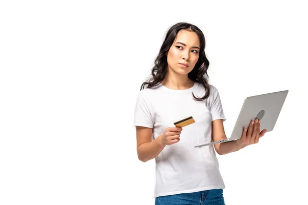 Mujer asiática seria en camiseta blanca sosteniendo tarjeta de crédito aislada en blanco - foto de stock