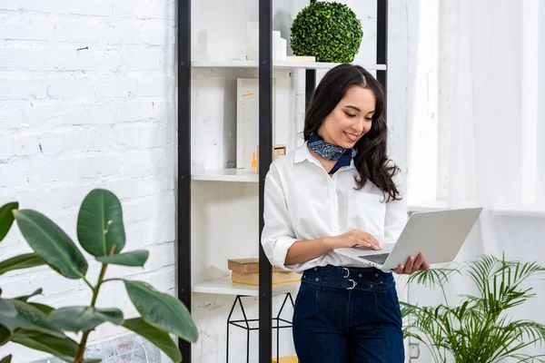 Young asian freelancer using laptop and writing in notebook and supporting head with hand — Stock Photo