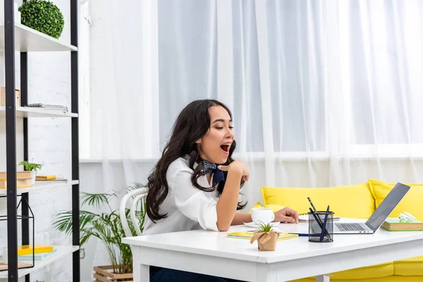 Exhausted sleepy asian freelance sitting at work desk and yawing — Stock Photo