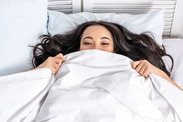 Young asian beautiful woman hiding under blanket — Stock Photo