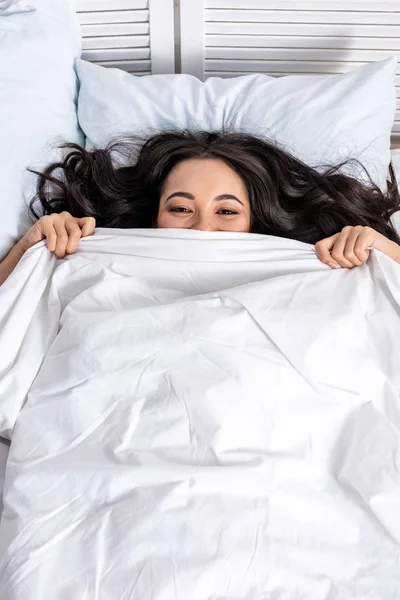 Young beautiful asian woman laughing while looking out of blanket — Stock Photo