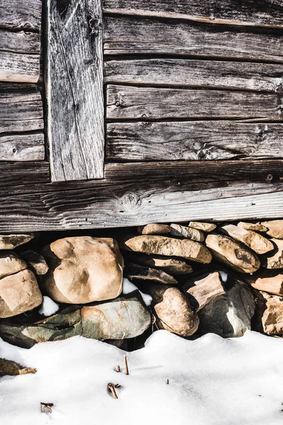Pila de rocas bajo casa de madera envejecida con luz solar - foto de stock