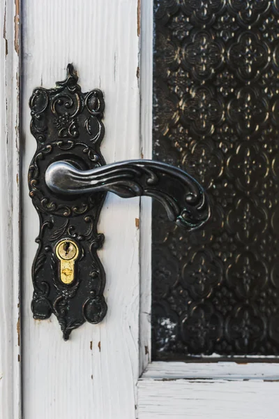 Close up of ironshod handle with lock on white wooden door — Stock Photo