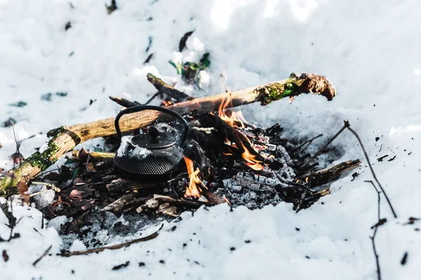 Boiling kettle with steam on bonfire in winter forest — Stock Photo