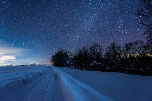 Céu escuro estrelado e estrada nevada nas montanhas dos Cárpatos à noite no inverno — Fotografia de Stock