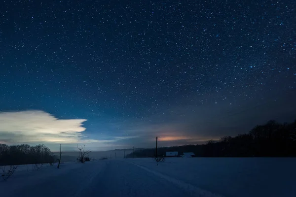 Céu escuro estrelado e estrada nas montanhas dos Cárpatos à noite no inverno — Fotografia de Stock