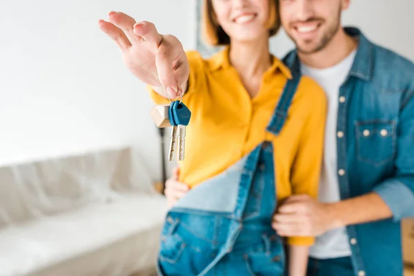 Selective focus of smiling couple showing keys at home — Stock Photo