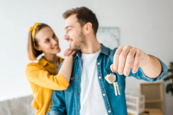 Selective focus of happy couple with keys at home — Stock Photo