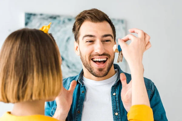 Mujer mostrando llaves a excitado marido en casa - foto de stock