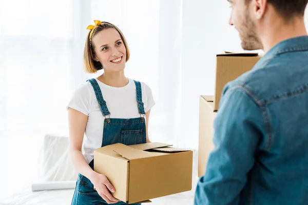 Cheerful couple holding cardboard boxes and looking at each other — Stock Photo