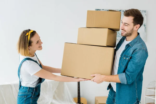 Happy couple holding cardboard boxes and looking at each other — Stock Photo